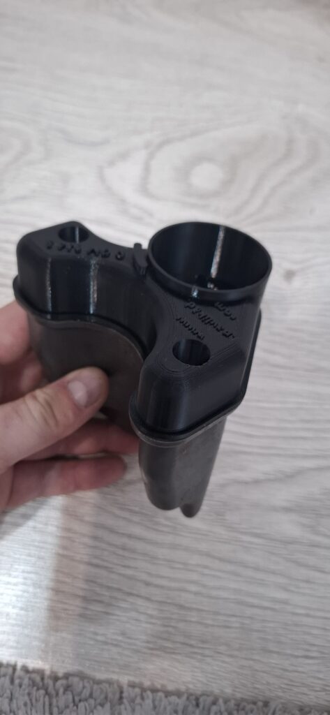 Nový čierny 3D tlačený diel držiaka filtra osadený na pôvodnej spodnej časti.