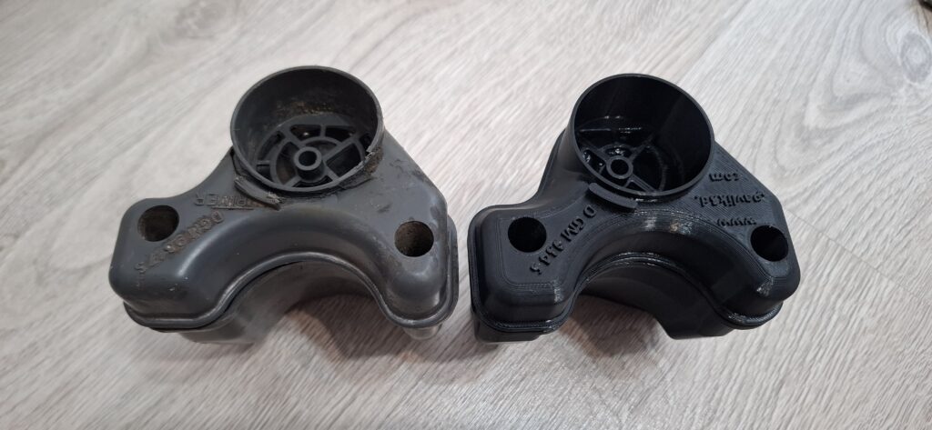 Porovnanie pôvodného sivého držiaka filtra a nového čierneho 3D tlačeného dielu.